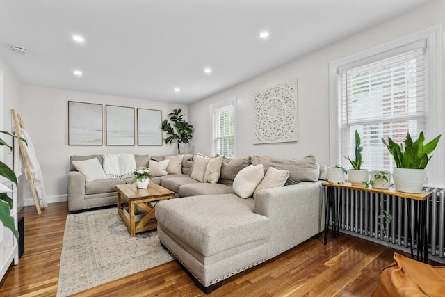 living area featuring radiator heating unit, baseboards, recessed lighting, and wood finished floors