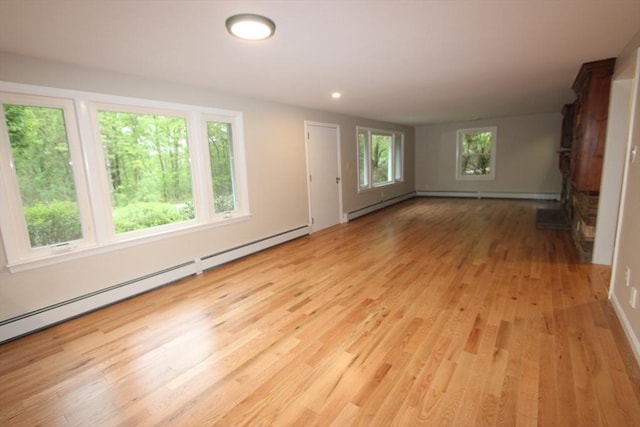unfurnished living room with a baseboard heating unit, light wood-style flooring, and recessed lighting