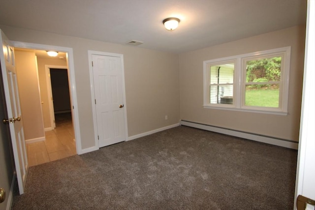 unfurnished bedroom featuring baseboard heating, carpet flooring, and baseboards
