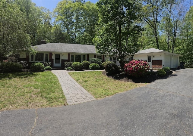 ranch-style house with a front lawn and asphalt driveway
