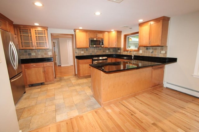 kitchen featuring stainless steel appliances, a sink, a peninsula, decorative backsplash, and recessed lighting