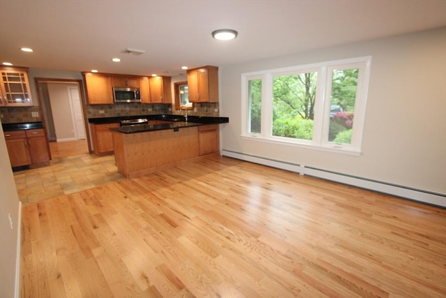 kitchen featuring stainless steel microwave, decorative backsplash, a peninsula, dark countertops, and glass insert cabinets