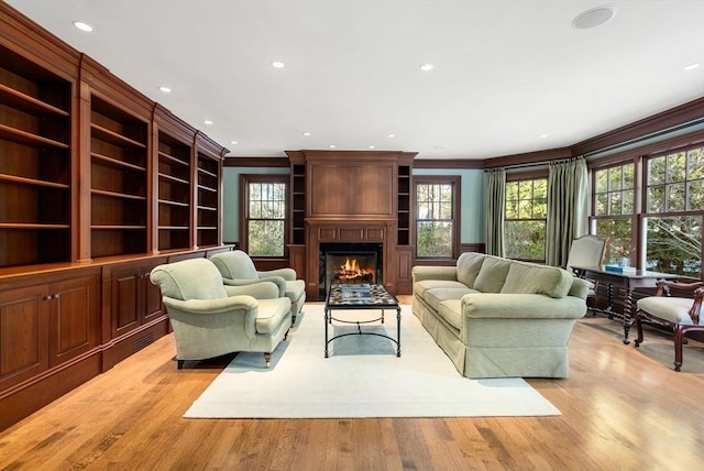 living room featuring ornamental molding, a fireplace, and light wood-type flooring