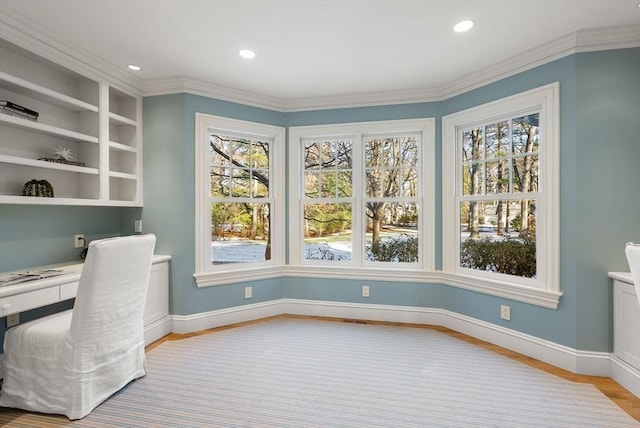 office area with built in shelves, ornamental molding, built in desk, and light hardwood / wood-style flooring