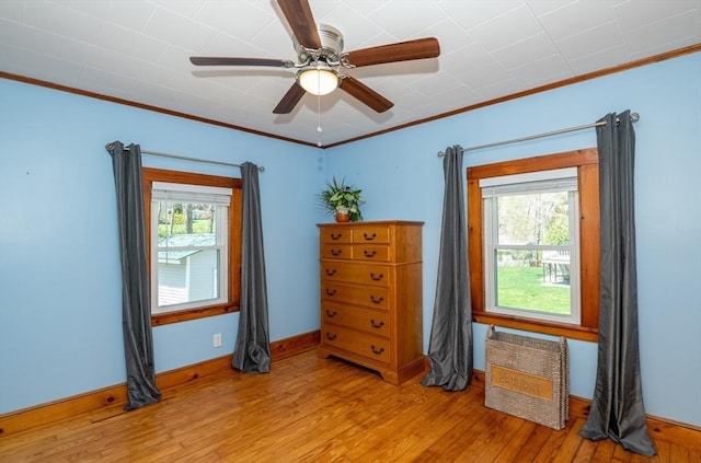 empty room with a ceiling fan, baseboards, ornamental molding, and light wood-style flooring