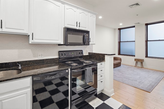 kitchen featuring black appliances, backsplash, white cabinetry, light hardwood / wood-style floors, and dark stone counters