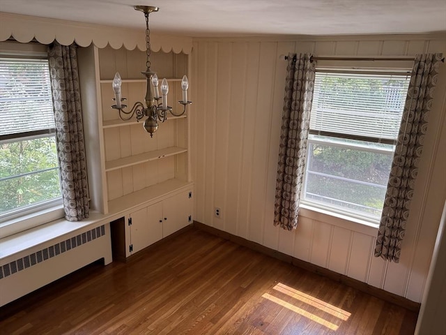 33 Meadowbrook Rd, Brookline, MA 02467 - unfurnished dining area featuring radiator, a chandelier, dark wood-style floors, healthy amount of natural light, and a decorative wall