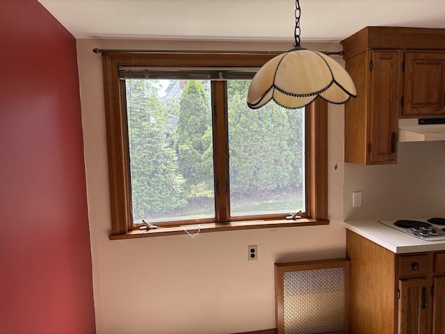 33 Meadowbrook Rd, Brookline, MA 02467 - kitchen with under cabinet range hood, white stovetop, light countertops, brown cabinets, and decorative light fixtures