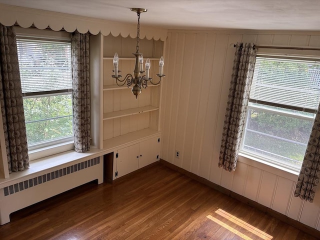 33 Meadowbrook Rd, Brookline, MA 02467 - unfurnished dining area with radiator heating unit, a chandelier, dark wood finished floors, and a decorative wall