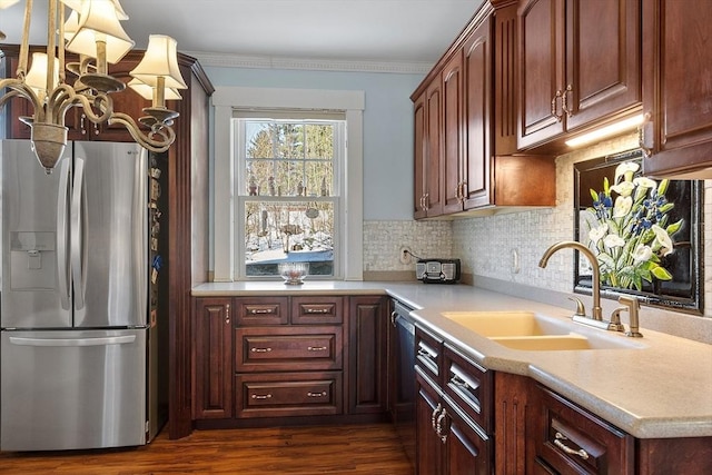 kitchen with dark wood-type flooring, sink, ornamental molding, stainless steel appliances, and backsplash