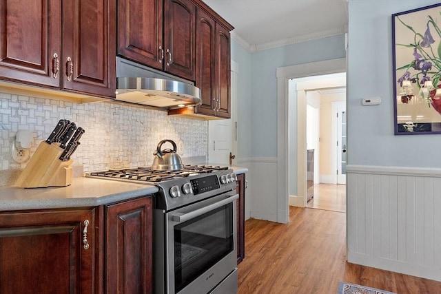 kitchen featuring light hardwood / wood-style flooring, backsplash, stainless steel gas range oven, and ornamental molding