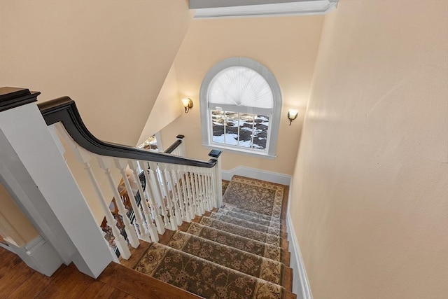 stairway featuring lofted ceiling and hardwood / wood-style flooring