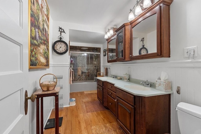 full bathroom with vanity, hardwood / wood-style floors, shower / bath combination with glass door, and toilet