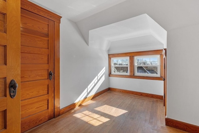 additional living space featuring lofted ceiling and light hardwood / wood-style floors