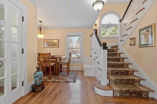 stairs featuring ornamental molding and hardwood / wood-style floors