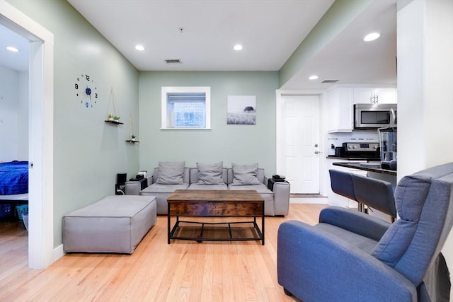 living area featuring light wood-style flooring and recessed lighting