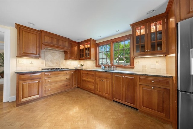 15 Hawthorne Rd, Hingham, MA 02043 - kitchen featuring appliances with stainless steel finishes, dark stone counters, brown cabinetry, a sink, and glass insert cabinets