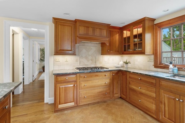 15 Hawthorne Rd, Hingham, MA 02043 - kitchen featuring stainless steel gas stovetop, dark stone counters, glass insert cabinets, decorative backsplash, and a sink