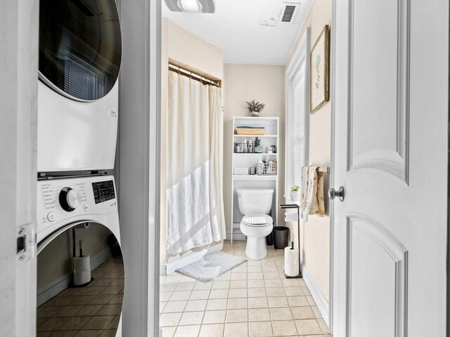 washroom featuring stacked washer and dryer and light tile patterned floors