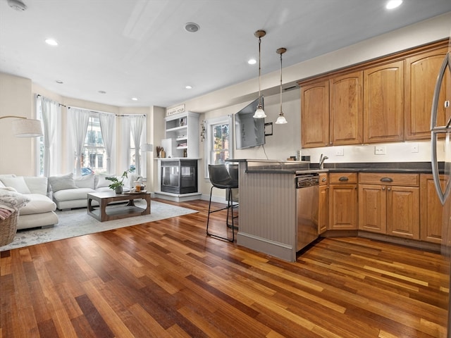 kitchen with plenty of natural light, decorative light fixtures, a breakfast bar area, and dark hardwood / wood-style flooring