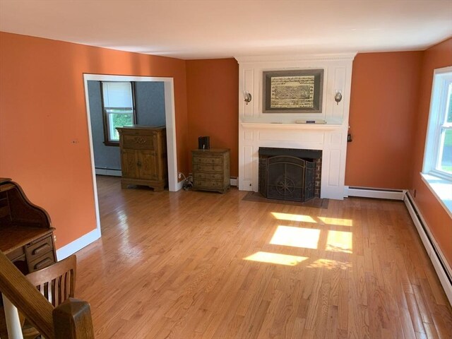 19 Locust Ave, Southbridge, MA 01550 - unfurnished living room with a baseboard heating unit, plenty of natural light, a fireplace, and a baseboard radiator