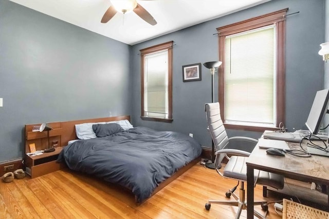 bedroom with baseboards, multiple windows, and wood finished floors
