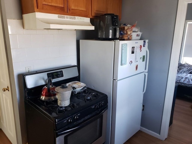 kitchen featuring decorative backsplash, dark hardwood / wood-style flooring, gas stove, and white fridge