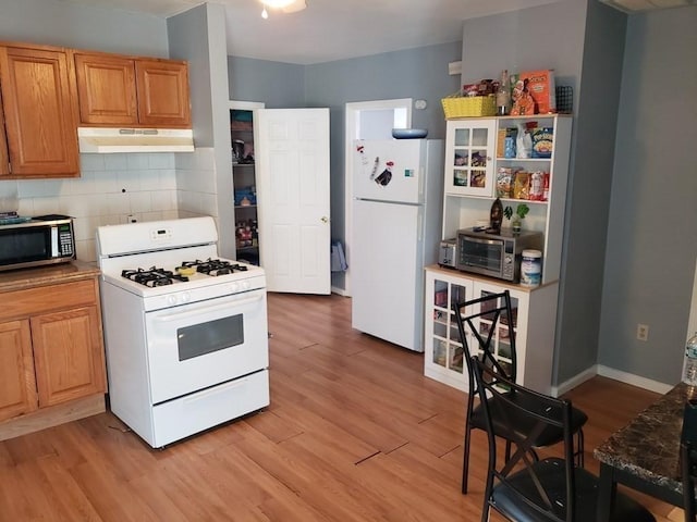 kitchen with decorative backsplash, light hardwood / wood-style floors, and white appliances