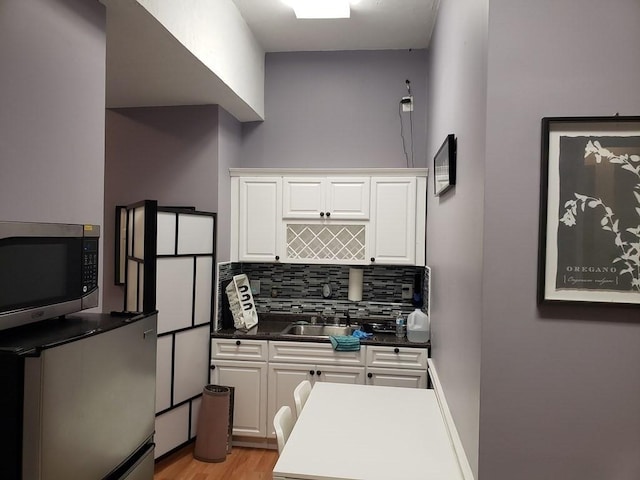 kitchen featuring decorative backsplash, white cabinetry, sink, and light hardwood / wood-style flooring