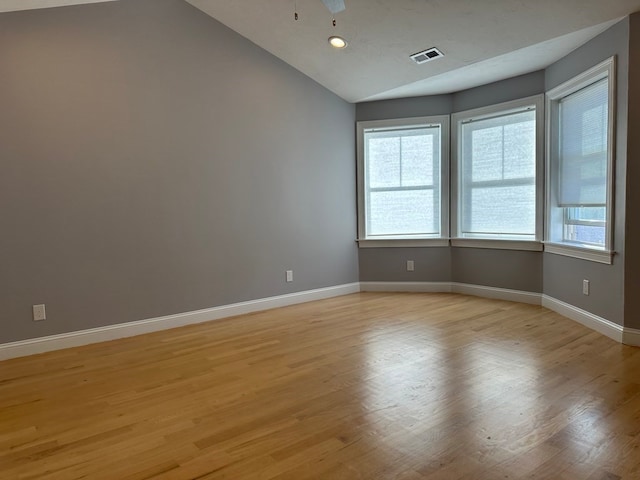 empty room with lofted ceiling, light hardwood / wood-style floors, and ceiling fan