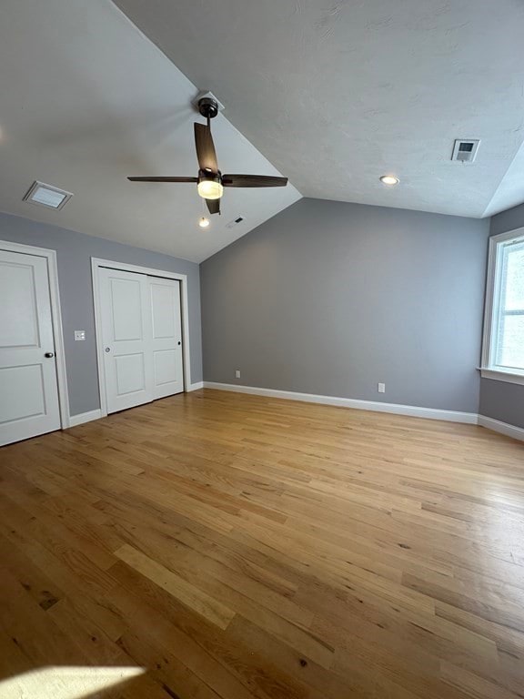 unfurnished bedroom featuring lofted ceiling, light wood-type flooring, and ceiling fan