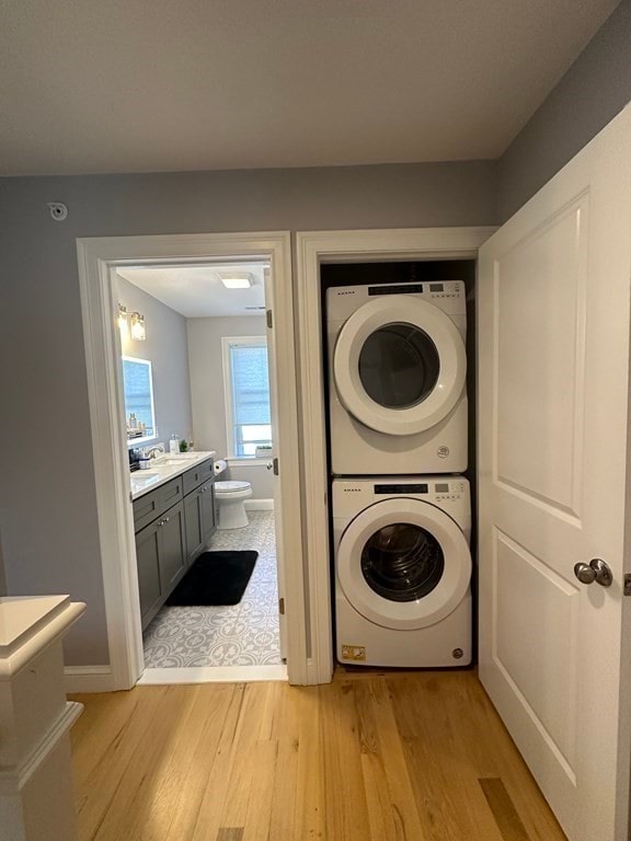 laundry area with stacked washer and dryer and light wood-type flooring