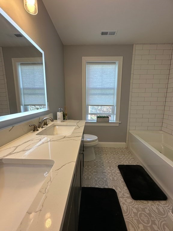 full bathroom with toilet, tiled shower / bath, vanity, and tile patterned floors