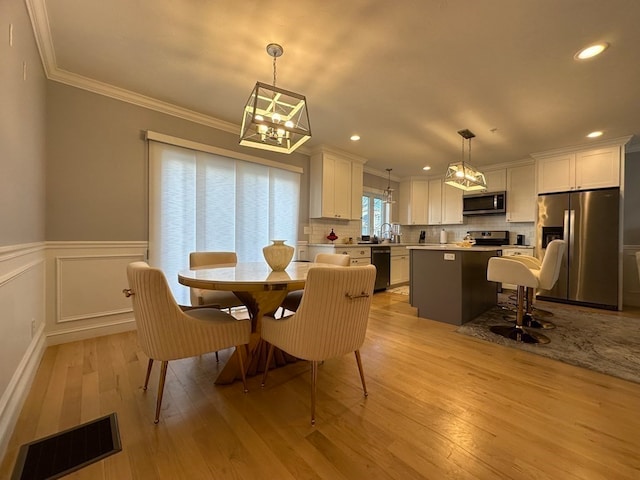 dining area with light hardwood / wood-style flooring, ornamental molding, and sink