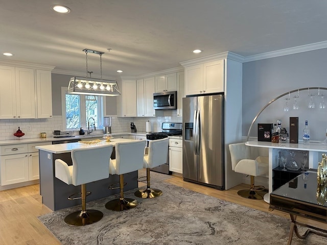 kitchen with appliances with stainless steel finishes, decorative light fixtures, and white cabinets