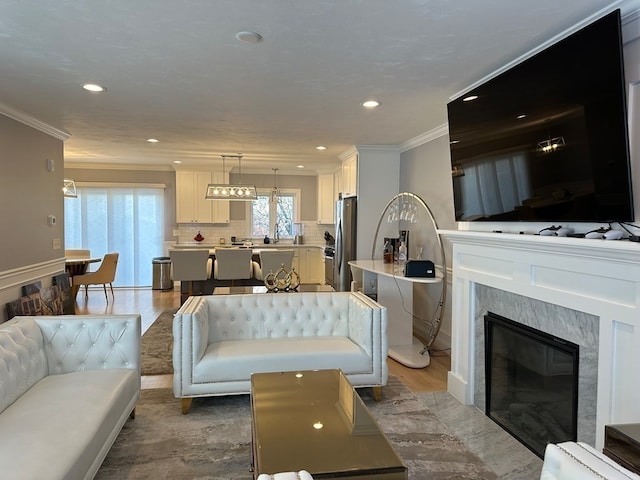 living room featuring a high end fireplace, hardwood / wood-style floors, and ornamental molding