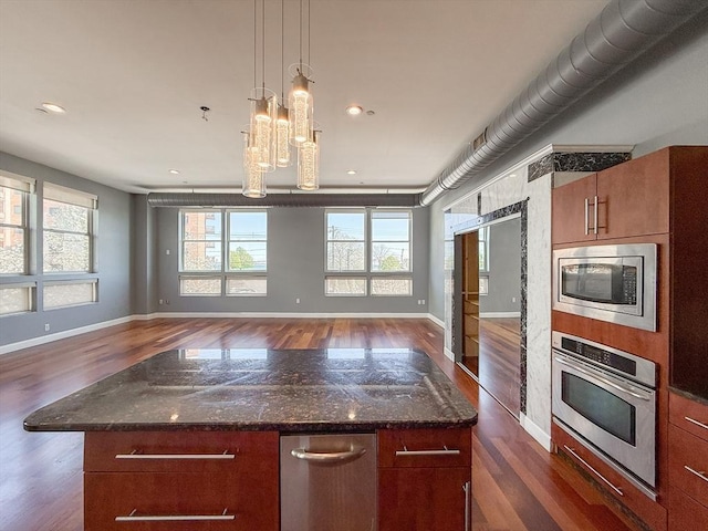 kitchen featuring baseboards, open floor plan, appliances with stainless steel finishes, and dark wood finished floors
