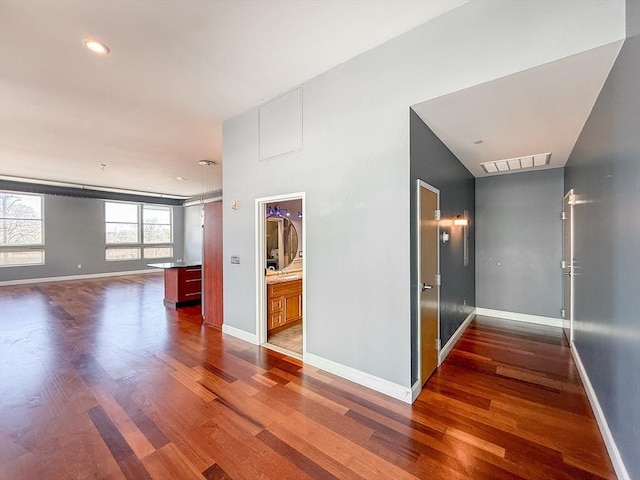 hallway with dark wood-type flooring, baseboards, and visible vents