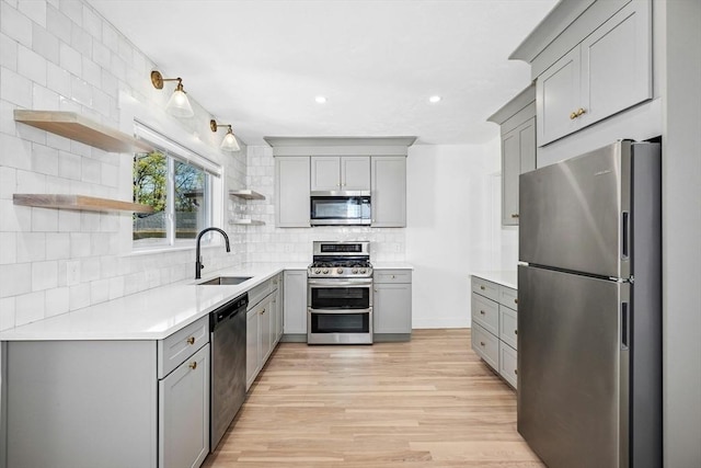 50 Mckinley St Unit 50, Maynard, MA 01754 - kitchen with appliances with stainless steel finishes, gray cabinets, open shelves, a sink, and light wood finished floors