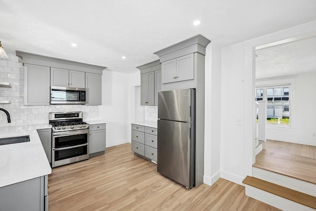 50 Mckinley St Unit 50, Maynard, MA 01754 - kitchen with appliances with stainless steel finishes, gray cabinets, backsplash, baseboards, and light wood finished floors