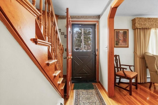 entryway featuring a healthy amount of sunlight, stairs, arched walkways, and wood finished floors