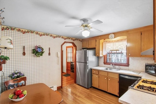 kitchen with freestanding refrigerator, light countertops, a sink, and dishwashing machine