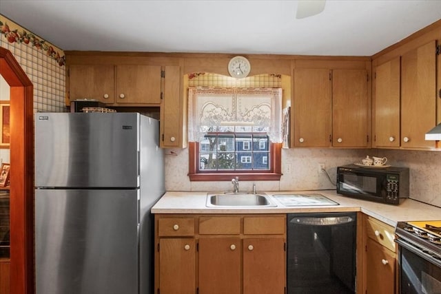 kitchen with black appliances, brown cabinetry, a sink, and light countertops