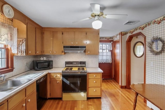 kitchen featuring light countertops, visible vents, a sink, under cabinet range hood, and black appliances