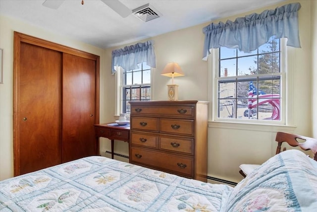 bedroom featuring a baseboard heating unit, ceiling fan, visible vents, and a closet