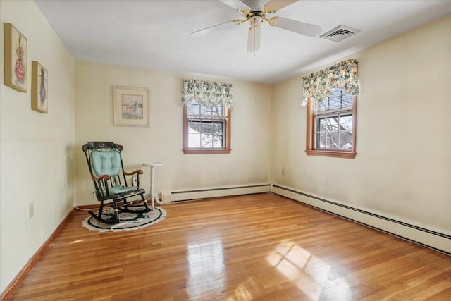 sitting room featuring visible vents, baseboard heating, and wood finished floors