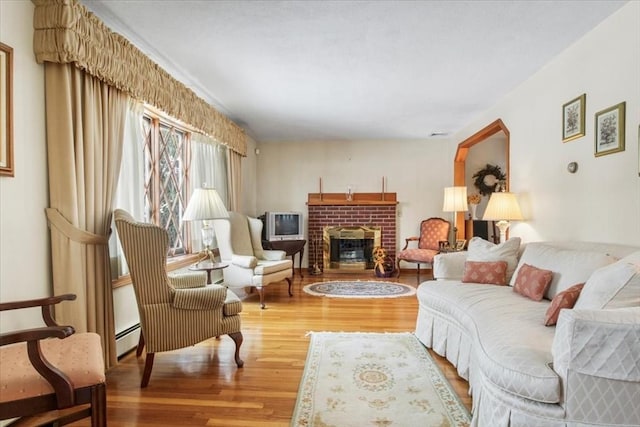 living room featuring a fireplace, baseboard heating, and wood finished floors