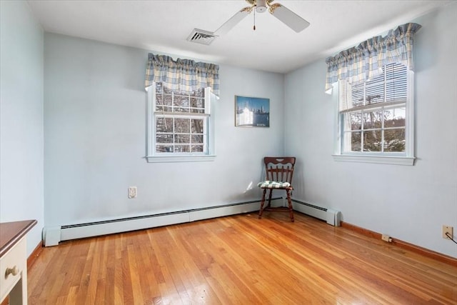 empty room with light wood finished floors, a baseboard radiator, visible vents, and a ceiling fan