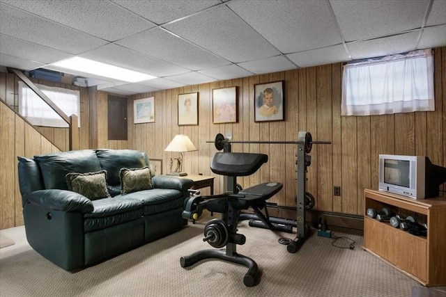 workout room featuring carpet, a paneled ceiling, and wooden walls