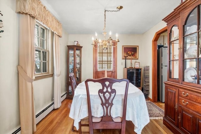 dining room with a baseboard heating unit, light wood-type flooring, a baseboard radiator, and an inviting chandelier